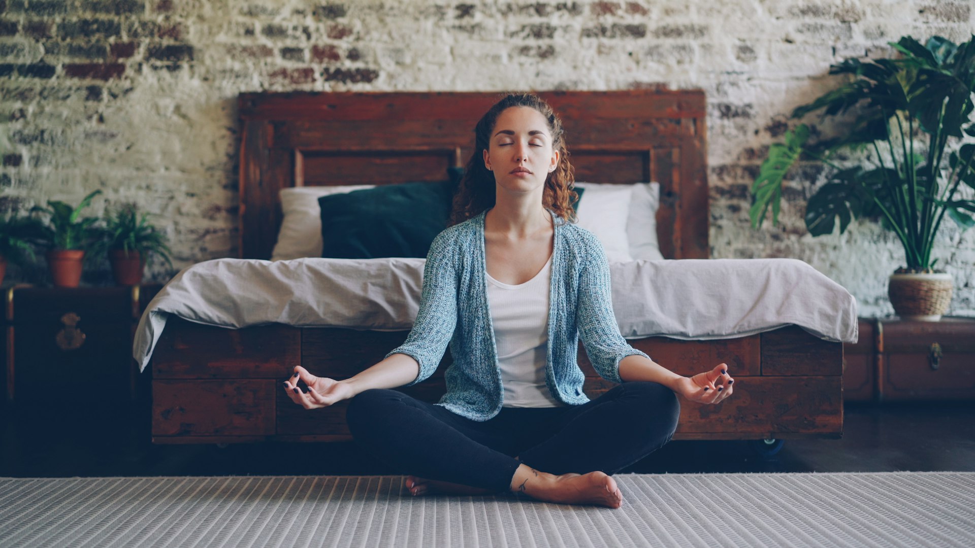 Woman meditating calmly at the foot of her bed