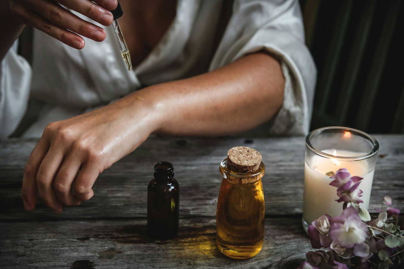 Amber essential oil bottles beside a lit candle