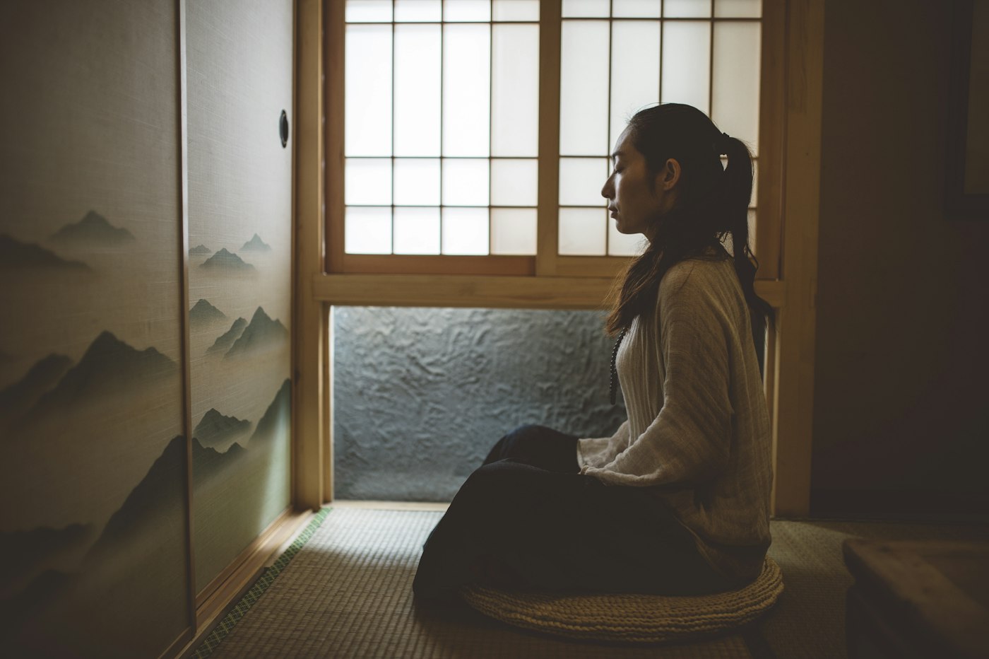 Woman sitting in quiet meditation beside a bright window