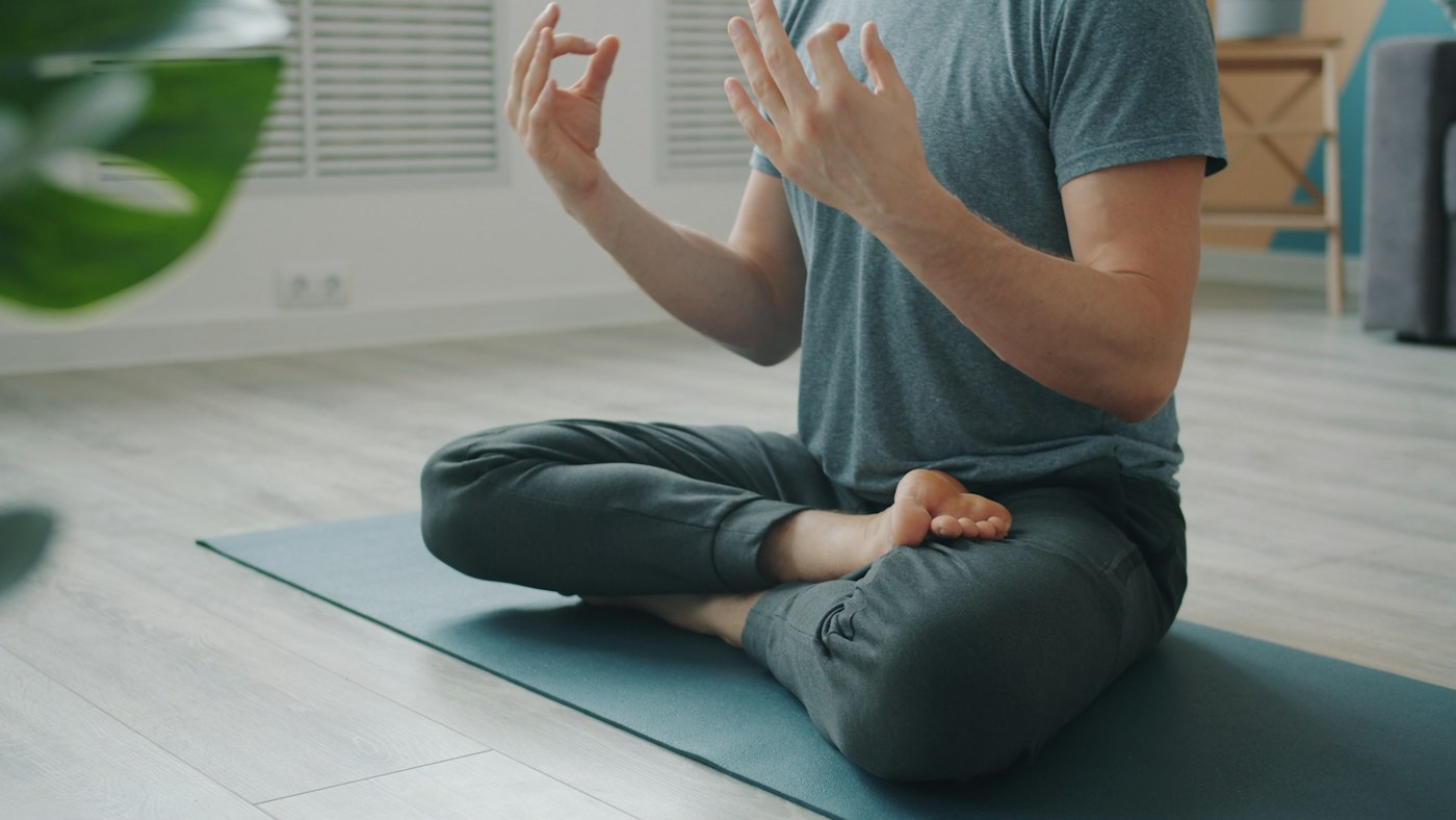 Man practising seated breathwork with relaxed hands on knees