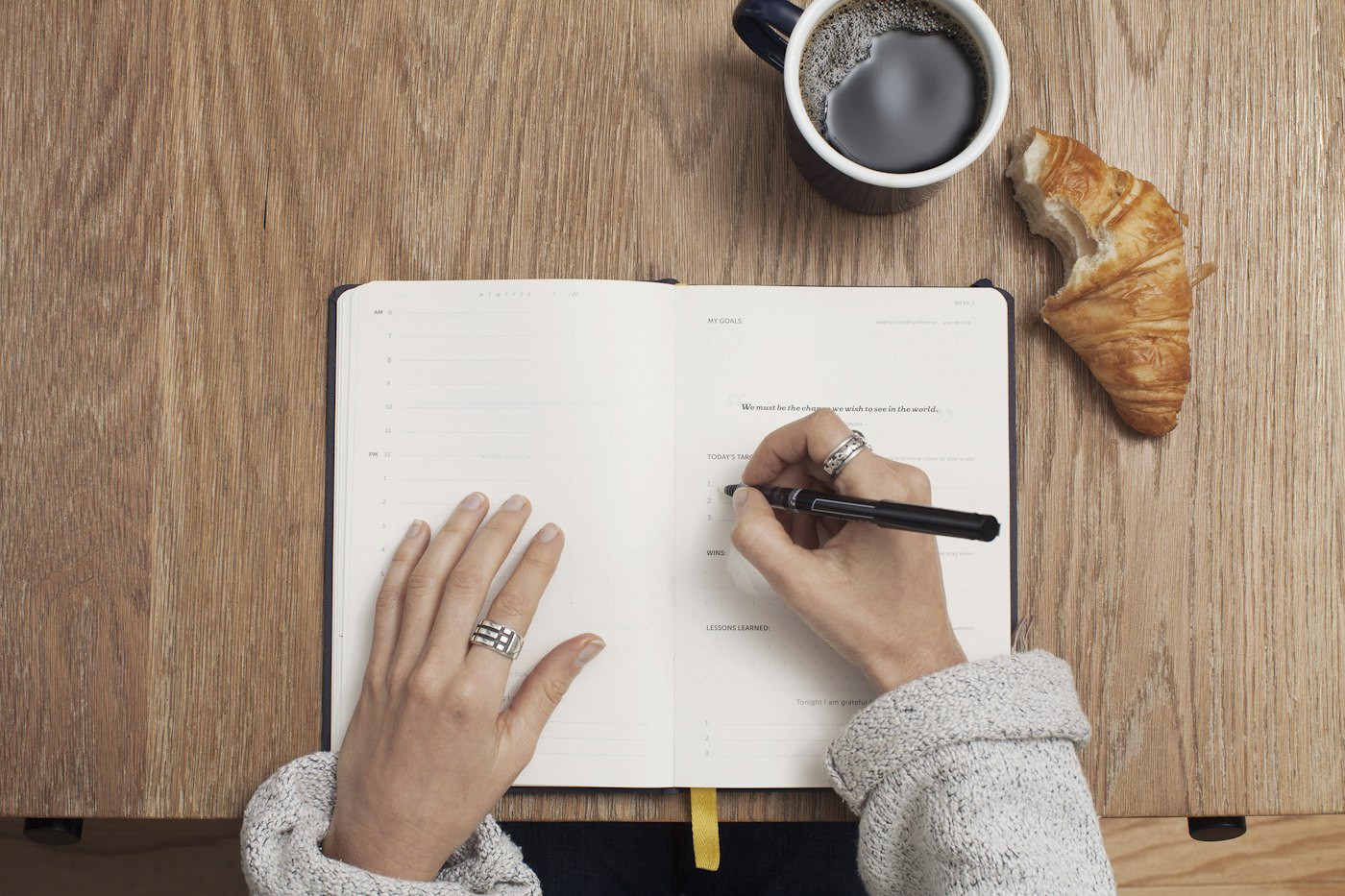 Hands writing wellness goals in an open notebook